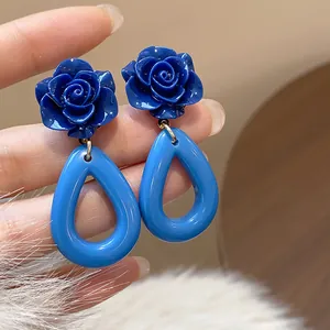 Vue macro montrant la texture détaillée des boucles d'oreilles rétro en acrylique bleu et gouttes