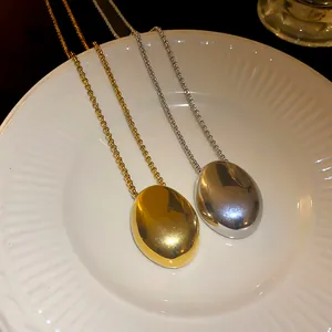 Macro view of gold and silver polished oval pendants on stainless steel necklaces