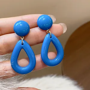 Vue rapprochée de boucles d'oreilles en acrylique bleu vif en forme de goutte.