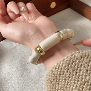 Detail view of swirl cylindrical elastic bracelet on wrist with gold spacers