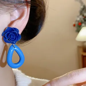 Gros plan de boucles d'oreilles rose en acrylique bleu avec pendentif goutte