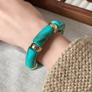 Close-up of bohemian marbled turquoise cylinder bead elastic bracelet with gold spacers
