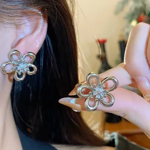 Detail view of minimalist zircon flower stud earrings with delicate silver plating.