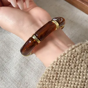 Detail of vintage cylindrical elastic bracelet with amber marbled resin segments.