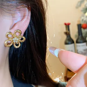 Macro close-up detail of elegant gold zirconia flower stud earrings worn on the ear