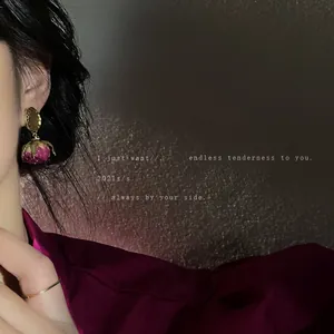 Elegant preserved rose drop earrings with gold studs shown on a model's ear