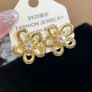 Close-up of elegant gold flower earrings with sparkling central zircons on display card