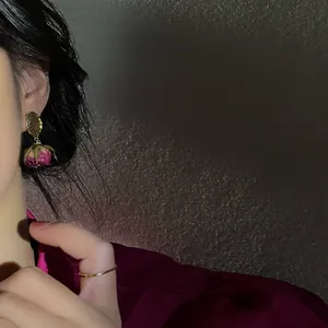 Detailed macro view of handmade preserved rose earrings in vintage French style