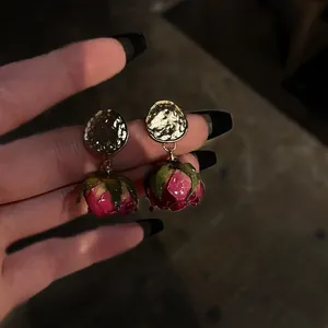 Detailed close-up of vintage preserved pink rose earrings with hammered gold discs