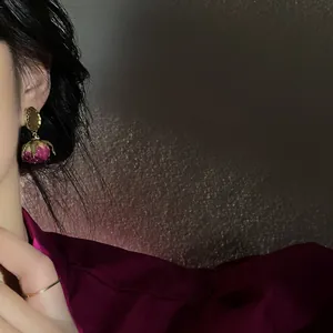 Detail view of vintage preserved rose earrings with gold metal accents worn by model