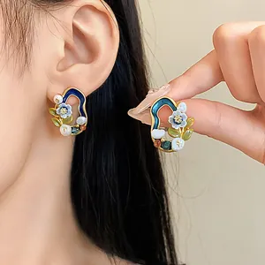 Nahaufnahme von Vintage-Ohrsteckern mit geometrischen Blumen, Perlen und Emaille
