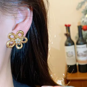 Detailed close-up showing a golden zirconia flower stud earring worn on a model's ear
