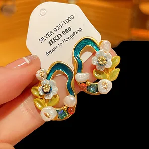 Detailaufnahme von Vintage-Blumenohrringen mit Süßwasserperlen und grünem Emaille-Finish.