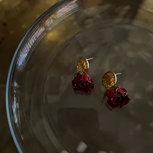 Close-up of vintage French style dark red rose earrings with gold stud detail on glass