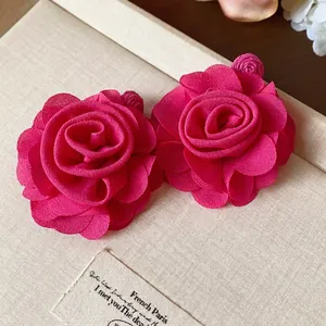 Elegant magenta chiffon rose flower stud earrings presented on a textured cream gift box