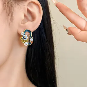 Detailansicht eines Vintage-Ohrrings mit blauer Emaille, weißer Blume und Perlen.