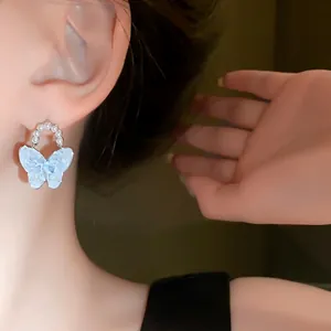 Elegante Schmetterlingsohrringe aus Kristall mit weißen Perlen für einen schicken Look.