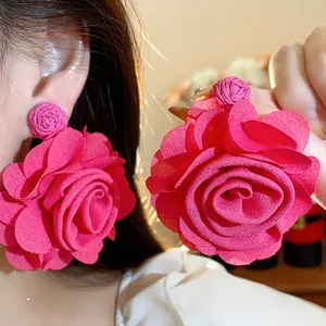 Close-up detail of oversized magenta chiffon flower earrings with raffia finish