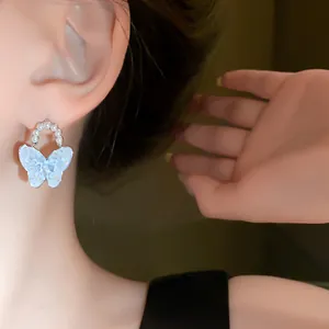 Nahaufnahme von Schmetterlings-Ohrringen mit Kristallen und Perlen für einen eleganten Stil