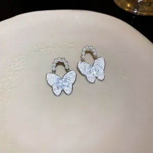 Detailansicht eleganter Schmetterlingsohrringe mit weißen Flügeln, Perlen und Kristalleinlage