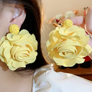 Detailed close-up of bright yellow raffia and chiffon rose flower earrings shown on ear