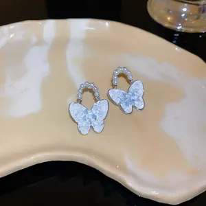 Detailaufnahme von eleganten Schmetterlingsohrringen mit Kristallen und Perlenbesatz