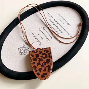Nahaufnahme des Retro-Leoparden-Anhängers aus Kunstleder auf literarischem Hintergrund
