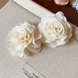 Detailed view of cream chiffon flower earrings with raffia woven accents
