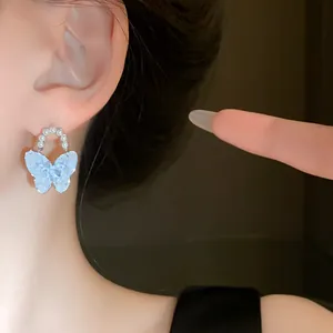 Detailansicht eleganter hellblauer Schmetterling Ohrringe mit Perlenreif am Modell