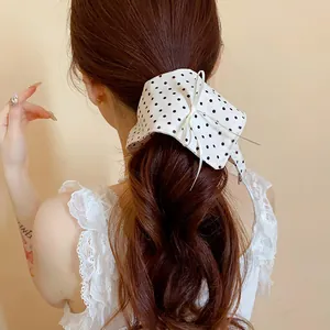 Dettaglio di un elastico per capelli a fiocco bianco a pois su una coda di cavallo bassa