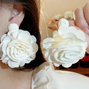 Detailed close-up showing texture of elegant white chiffon flower earrings with raffia