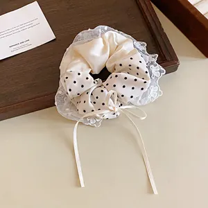 Dettaglio di uno scrunchie crema a pois stile francese con pizzo e un fiocco elegante