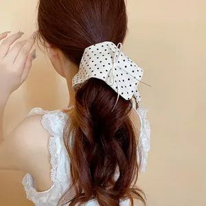 Vista dettagliata di un elastico per capelli a pois bianchi con un elegante fiocco