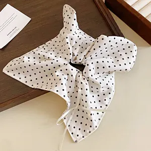 Primo piano di un elastico per capelli a fiocco bianco a pois con nastro delicato