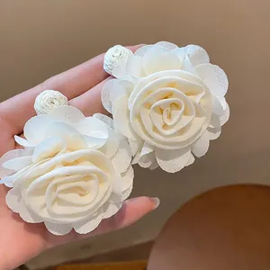 Close-up of white chiffon rose earrings with intricate petal details and raffia bead