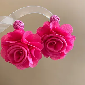 Macro detail of pink chiffon rose earrings featuring intricate raffia wrapped studs
