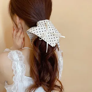 Primo piano di un elastico per capelli a pois bianchi con un fiocco decorativo.