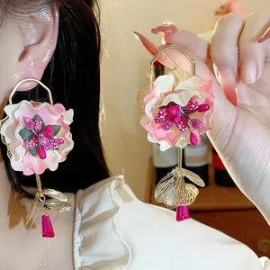 Detail view of pink fabric flower earrings with gold leaf and crystal drops