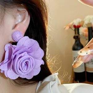Detailed macro shot of elegant purple chiffon flower statement earrings on model