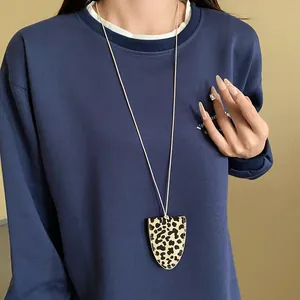 Detaillierte Ansicht einer Lederkette mit Leopardenmuster auf einem dunkelblauen Pullover