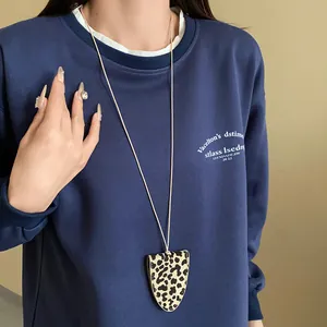Detailansicht einer dreieckigen magnetischen Brillenhalskette mit Leopardenmuster auf einem Pulli.