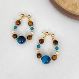 Gros plan de boucles d'oreilles vintage en œil de tigre et perles avec détails dorés
