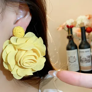Close-up detail of oversized yellow chiffon flower statement earrings on model