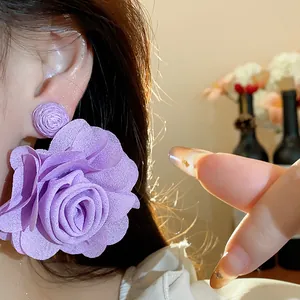 Close-up showing a large purple chiffon flower earring with raffia stud on a woman's ear
