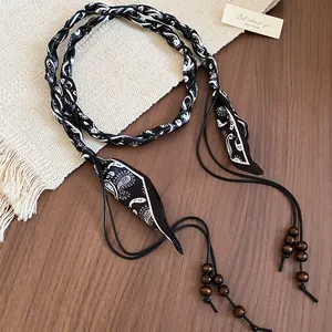 Close-up detail of bohemian fabric waist belt with paisley pattern and wooden beads decor