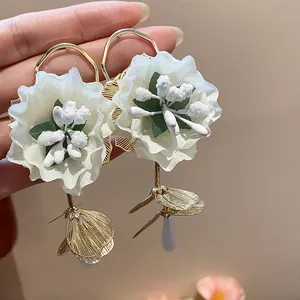 Detailed view of handmade white fabric flower earrings with elegant gold metal accents