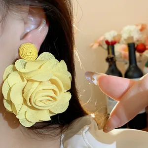 Detail view of a large yellow chiffon rose flower earring with raffia woven top part