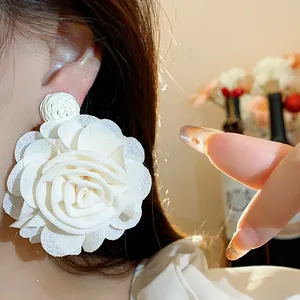 Detail shot of a large white raffia and chiffon flower earring on a model's ear
