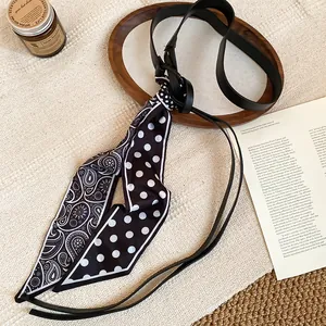 Close-up of vintage black leather belt with polka dot and paisley scarf detail
