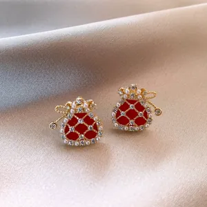 Dettaglio macro di eleganti orecchini a sacchetto rossi con perle e strass su seta